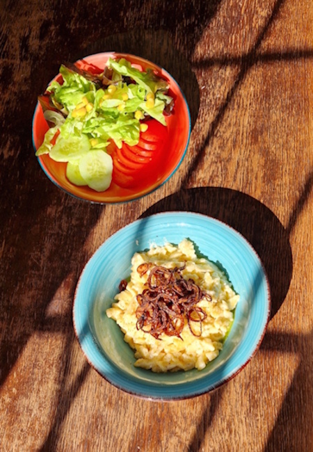handgeschabte spätzle mit käsemischung und obendrauf röstzwiebeln, daneben steh ein kleiner gemischter salat mit tomate, gurken blattsalat und mais